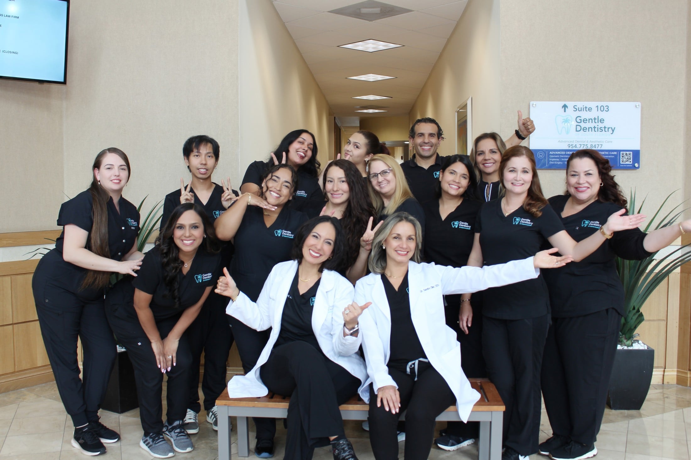 Group portrait of the Gentle Dentistry staff posed together in a hallway, including two dentists in white lab coats seated in front